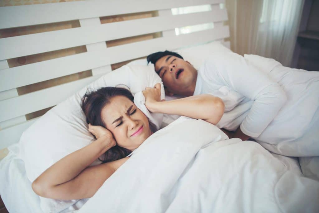 A woman covering hear ears because of snoring